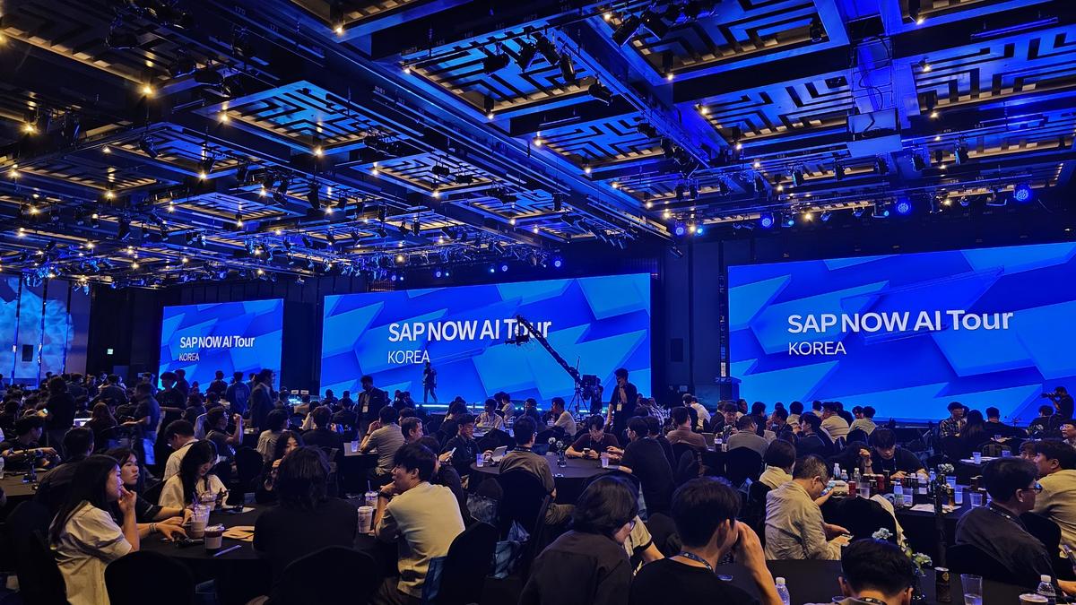 SAP NOW AI Tour 2025 Korea 행사장 전경. 대형 스크린에 행사 로고가 떠 있고 원형 테이블마다 참석자들이 가득 차 있다